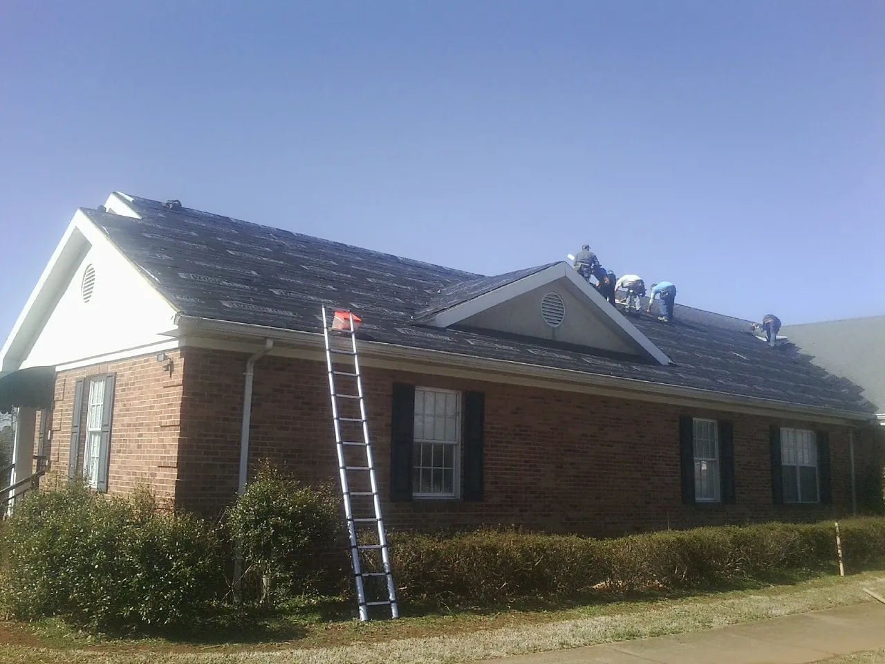 Crew tearing shingles off a brick ranch roof with a ladder set — Metal Roof Repair work by our crew in Newhall