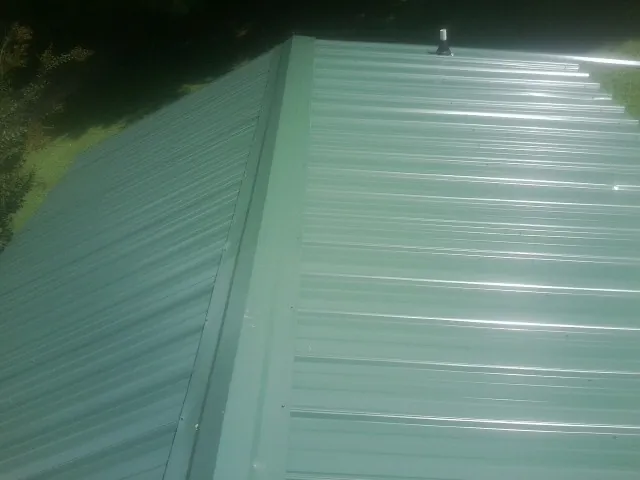 New green metal panels meeting at the ridge of a roof — Flat Roof Repair work by our crew in Newhall