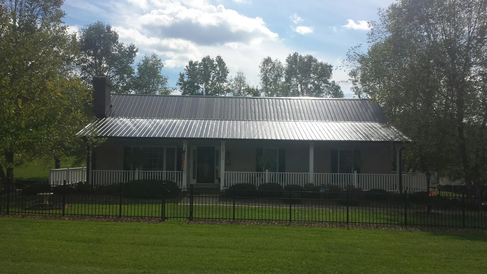 Gray metal roof on a brick ranch with a full width front porch — Gutter Guard Installation work by our crew in Newhall